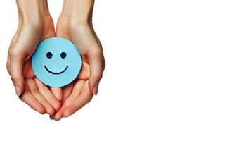 A pair of hands gently holding a blue circle with a simple, happy face drawn on it on white background photo