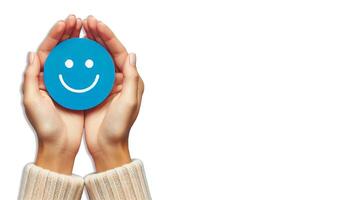 A pair of hands gently holding a blue circle with a simple, happy face drawn on it on white background photo