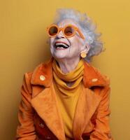 Smiling Senior Woman In Yellow Coat And Sunglasses Against Yellow Background photo