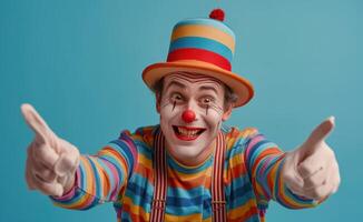 Happy Clown Wearing Striped Shirt and Hat Pointing With Finger Against Blue Background photo