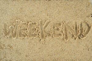 weekend hand writing on sand background photo