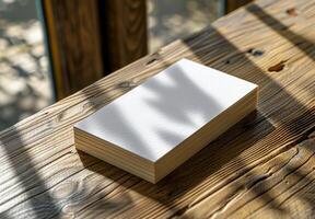 Blank White Paper Stack on Rustic Wooden Table in Sunlight photo