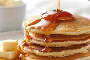 Stack of Pancakes Being Drizzled With Syrup on White Plate photo