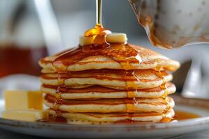 Stack of Pancakes Being Drizzled With Syrup on White Plate photo