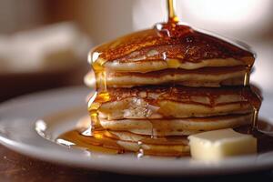 Stack of Pancakes Being Drizzled With Syrup on White Plate photo