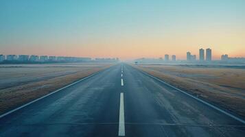 Empty Road Leading Towards A City Skyline During Sunrise photo