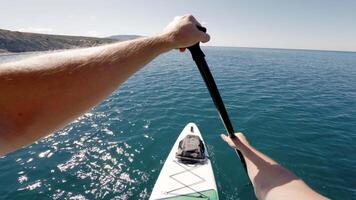Men rowing on sup board on summer quiet sea. First person view of stand paddle boarding. video