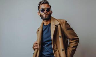 Man Wearing a Tan Overcoat and Sunglasses Posing Against a White Background photo