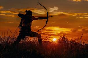 Silhouette of an Archer Aiming at Sunset in a Field of Grass photo