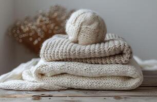 Stacked Beige Knitted Sweaters and Yarn Ball on a Wooden Table photo