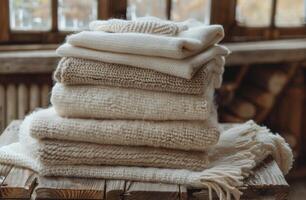 Stack of Knitted Blankets on a Wooden Table Near a Window photo