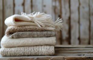 Stack of Knitted Blankets on a Wooden Table Near a Window photo