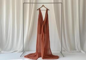 Rust Colored Sheer Blouse With Bell Sleeves Hanging on a White Hanger photo