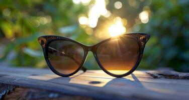 Black Cat Eye Sunglasses Resting on Wooden Table During Sunset photo
