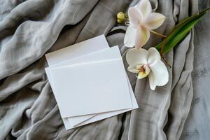 Blank White Cards Resting on a Soft Beige Fabric With White Orchids photo