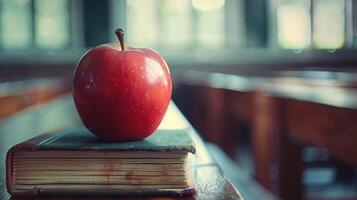 A Red Apple Resting on a Textbook in a Classroom photo