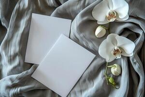 Blank White Cards Resting on a Soft Beige Fabric With White Orchids photo