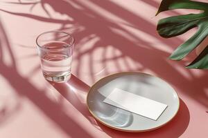 Glass of Water and White Card on Plate With Palm Leaf Shadows photo