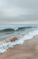 Gentle Ocean Wave Crashing on Sandy Beach Under a Cloudy Sky photo