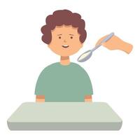 Happy boy sitting at table and eating from spoon held by someone out of frame vector