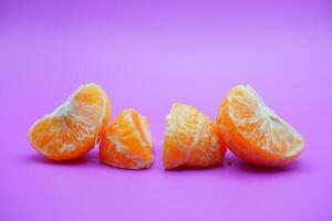 oranges that have been peeled and divided into several parts. orange isolated on purple background photo