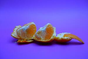 orange and peel isolated on purple background photo