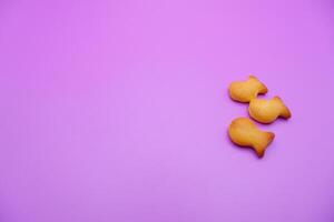 three biscuits shaped like fish isolated on a purple background photo