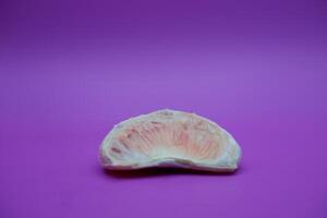 a slice of grapefruit isolated on a purple background. peeled grapefruit photo