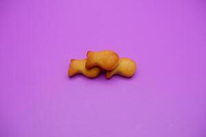 three biscuits shaped like fish isolated on a purple background photo