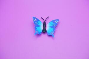 butterfly toy isolated on purple background. toy butterfly with blue wings. photo