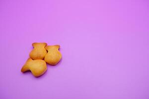 three biscuits shaped like fish isolated on a purple background photo