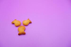 three biscuits shaped like fish isolated on a purple background photo