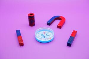 magnet and compass isolated on purple background photo