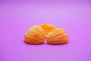oranges that have been peeled and divided into several parts. orange isolated on purple background photo