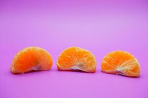 oranges that have been peeled and divided into several parts. orange isolated on purple background photo