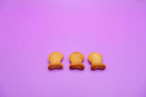 three biscuits shaped like fish isolated on a purple background photo