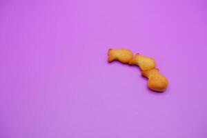 three biscuits shaped like fish isolated on a purple background photo