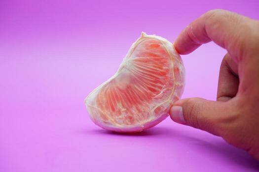a slice of grapefruit isolated on a purple background. peeled grapefruit photo