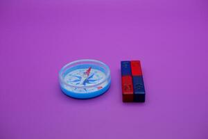 magnet and compass isolated on purple background photo