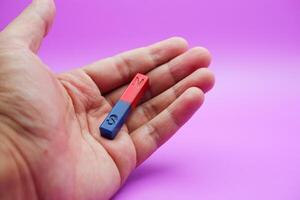 hand holding a bar magnet isolated on a purple background photo