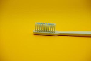white toothbrush isolated on dark yellow background photo