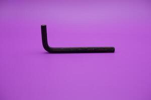 Allen key isolated purple background. a black L key. photo
