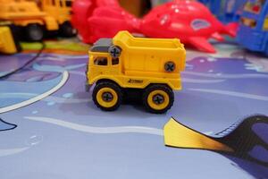 Side view of a yellow truck toy car with a blurry toy background photo