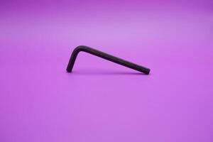 Allen key isolated purple background. a black L key. photo