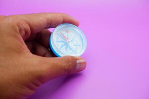 hand holding a compass isolated on a purple background photo