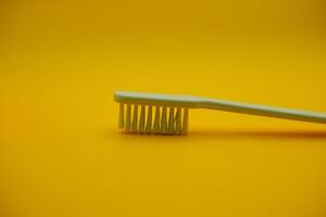 white toothbrush isolated on dark yellow background photo
