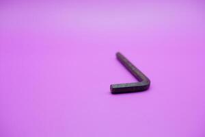 Allen key isolated purple background. a black L key. photo
