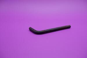 Allen key isolated purple background. a black L key. photo