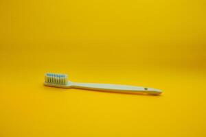 white toothbrush isolated on dark yellow background photo