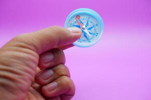 hand holding a compass isolated on a purple background photo